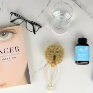 Younger book by Dr. Lancer next to glasses and bottles of HUM Nutrition supplements for skin and anti-aging