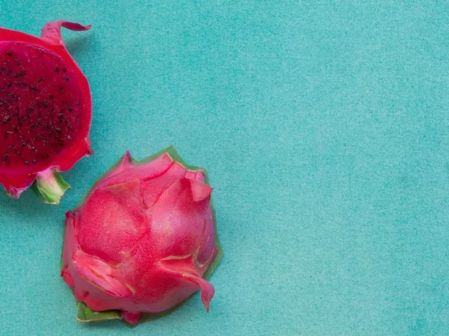 Cut open dragonfruit on aqua background