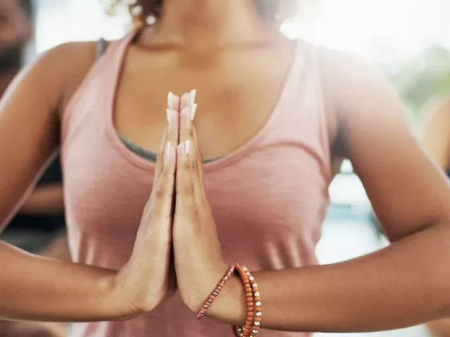 Woman with hands to heart in an Ayurvedic class