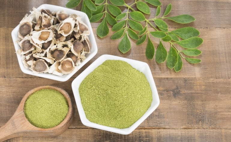 Pó de moringa a partir de sementes e folhas sobre mesa de madeira