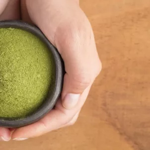 Woman holding bowl of green superfood moringa powder