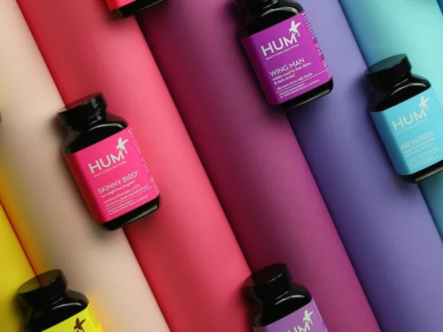 HUM Nutrition supplement bottles on rainbow background