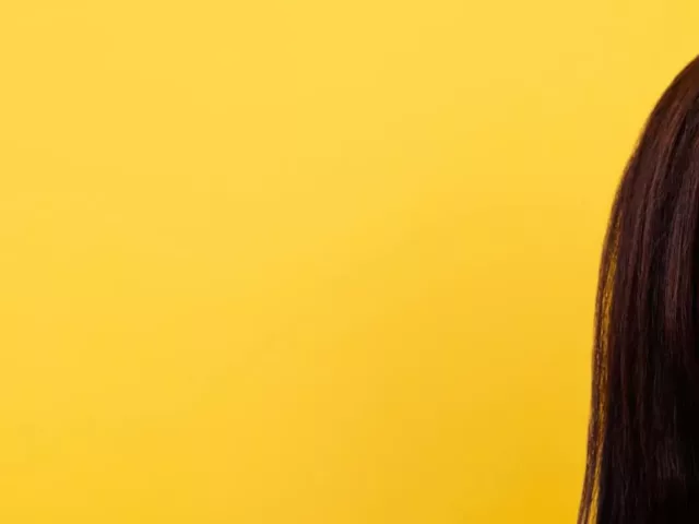 Woman with beautiful skin and eyes closed in front of yellow backdrop