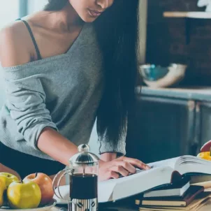 Woman in draped sweater and underwear preparing a meal from a sexy cookbook