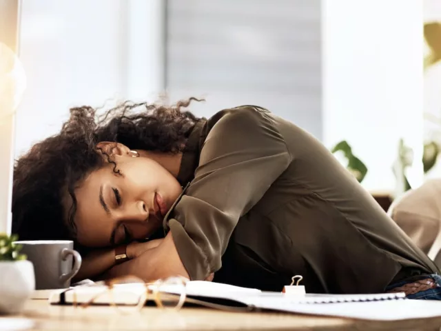 Woman with vitamin B12 deficiency asleep at desk