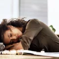 Woman with vitamin B12 deficiency asleep at desk