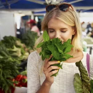 Woman smelling fresh mint at farmer's market before meal prep