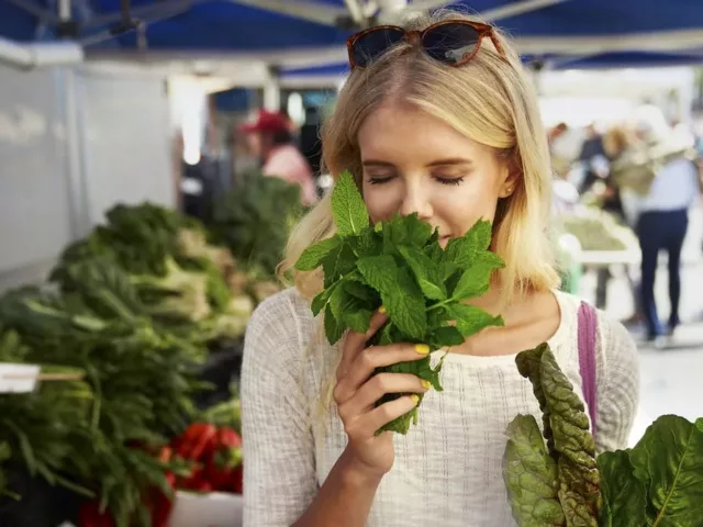 Woman smelling fresh mint at farmer's market before meal prep