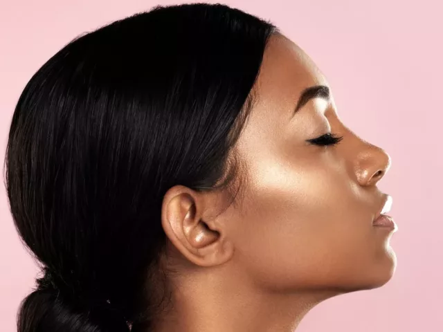 Profile of woman with glowing skin on pink background