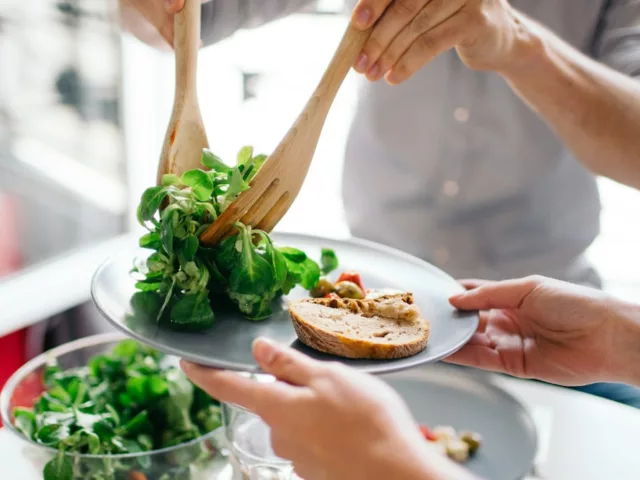 Person doling out healthy plate portions for a well-balanced meal