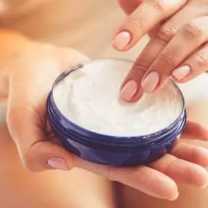 Woman applying Kaplan MD night cream from a jar