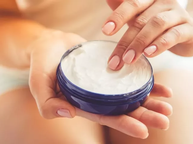 Woman applying Kaplan MD night cream from a jar