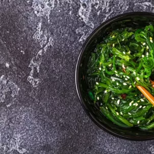 Bowl of seaweed with wooden chopsticks on slate table