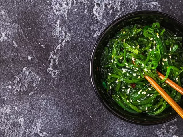 Bowl of seaweed with wooden chopsticks on slate table