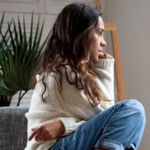 Woman curled into a ball on chair, biting her nails