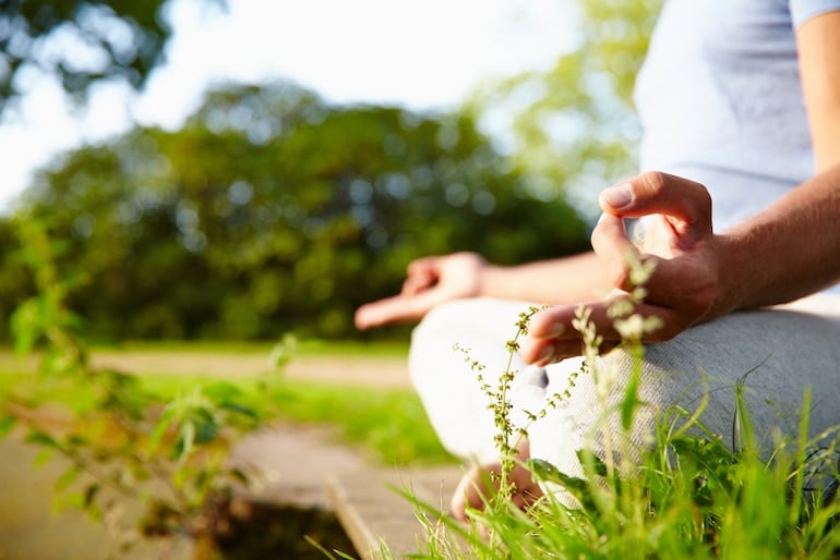 Man meditating outside in grass