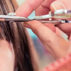 Hairdresser cutting woman's bangs