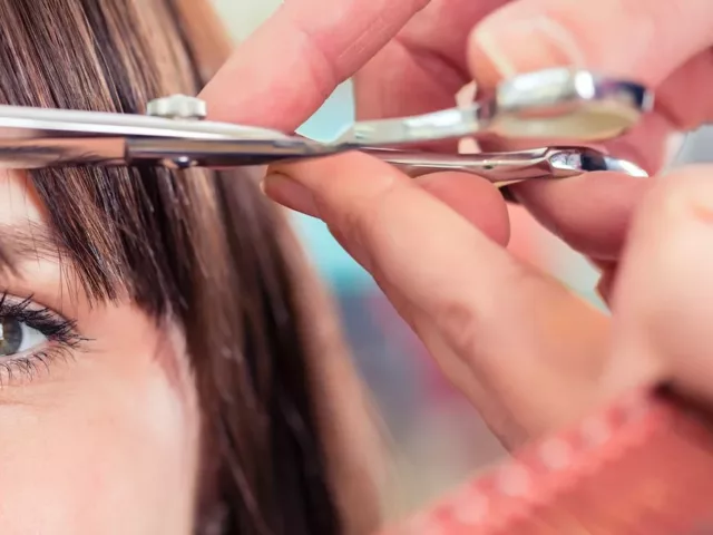 Hairdresser cutting woman's bangs