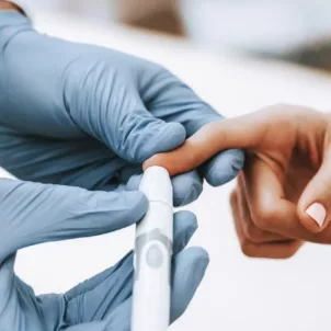 Doctor in gloves checking a woman's triglyceride levels with a finger blood test