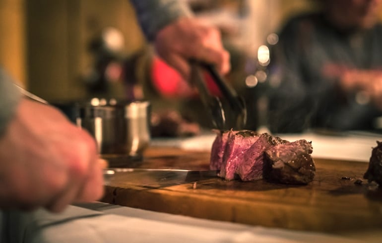 Man cutting steak after taking a bromelain supplement to improve digestion of protein