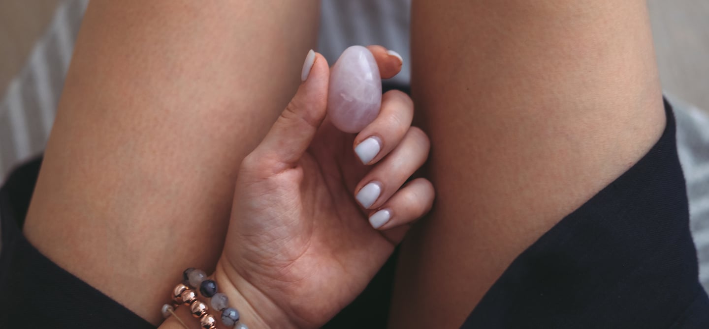 Jade Egg Practice for Women - Healing Tao Australia. A womens hand holding a yoni egg. Text displays multiple orgasms, increased libido, magnetic sexual energy