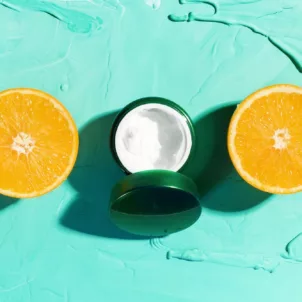 Skincare Acid Moisturizer flanked by 4 sliced oranges