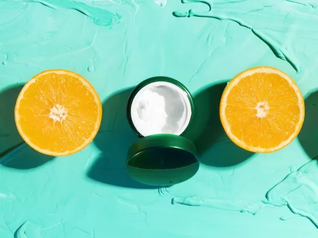 Skincare Acid Moisturizer flanked by 4 sliced oranges