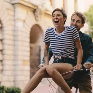 Woman riding on handlebars of her boyfriend's bike