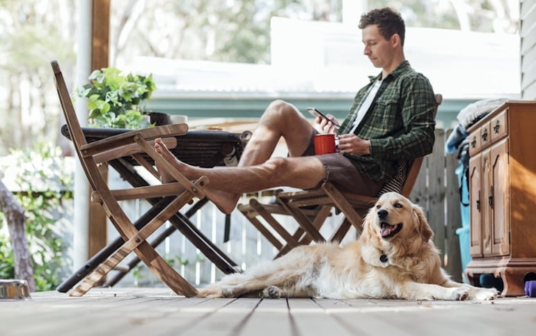 Man relaxing on his porch with his dog, enjoying the adaptogenic effects of ashwagandha to manage stress