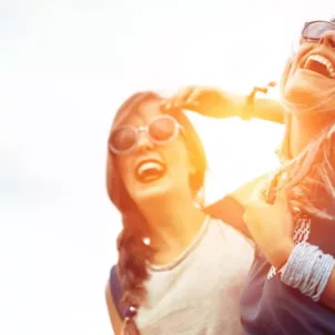 Two friends having fun wearing sunglasses at a music festival