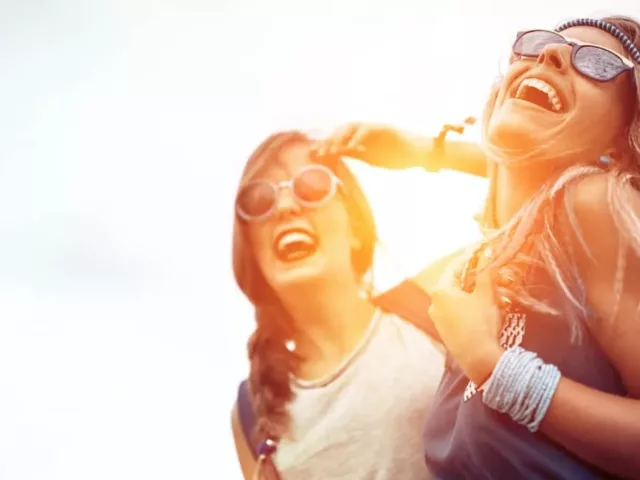 Two friends having fun wearing sunglasses at a music festival