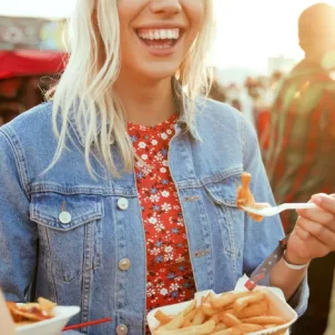 Woman at music festival smiling and eating fries