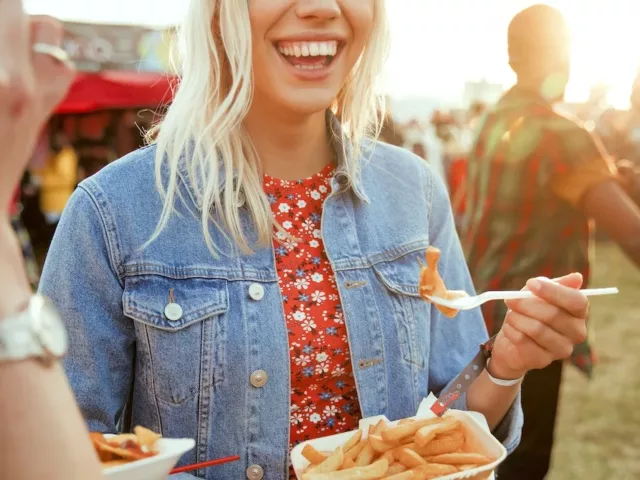 Woman at music festival smiling and eating fries