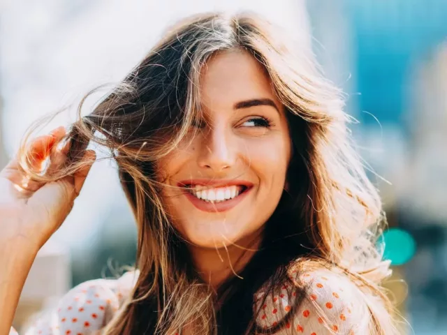 Woman smiling with healthy hair blowing in the wind