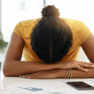 Dark-haired woman exhausted from work burnout resting her head at her desk