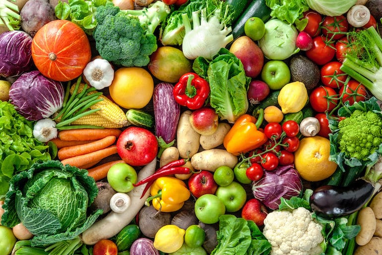 Table full of colorful fruits and veggies, which you should eat on the satiating diet to lose weight