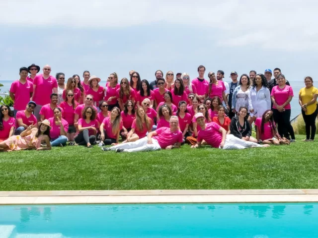 Group photo of HUM Nutrition team in pink shirts in front of pool in Malibu