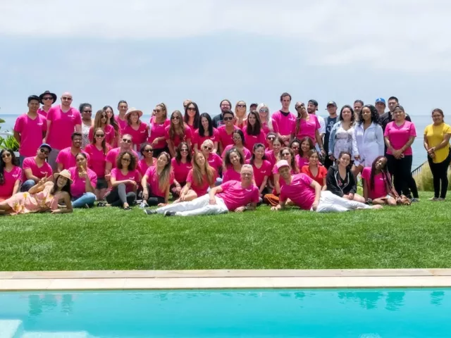 Group photo of HUM Nutrition team in pink shirts in front of pool in Malibu