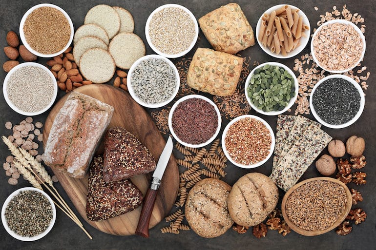 Table setting of high-fiber whole grains, including bread, seeds, and pasta