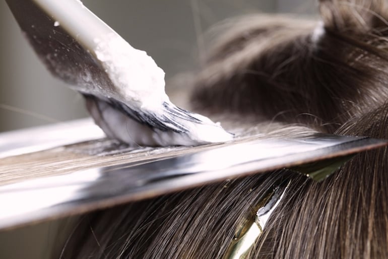 Woman getting her hair highlighted; chemicals can lead to hair damage and breakage