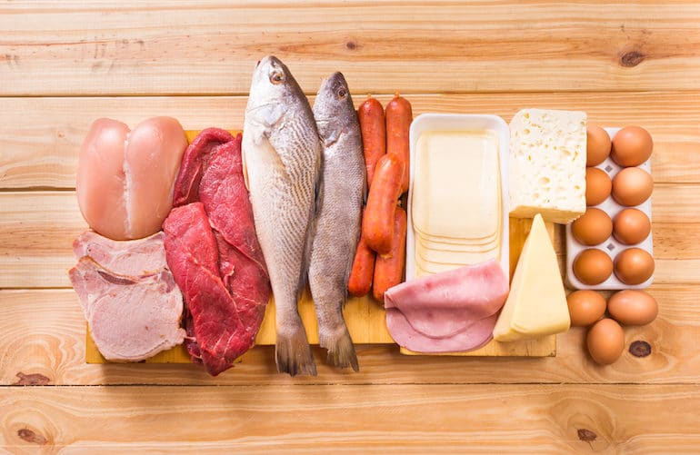 sources of lean protein on a wooden table, including chicken, fish, and eggs