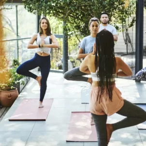 Small group yoga class performing tree pose on outdoor patio