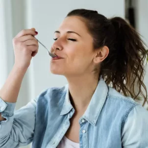 Woman eating spoonful of healthy snacks with glee