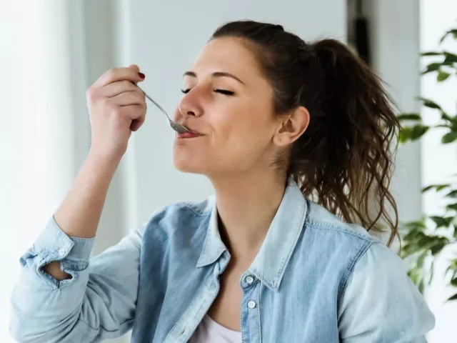 Woman eating spoonful of healthy snacks with glee