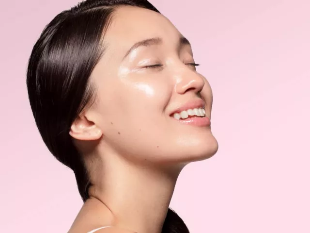 Profile shot of woman with beautiful clear glass skin on light pink background