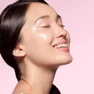 Profile shot of woman with beautiful clear glass skin on light pink background