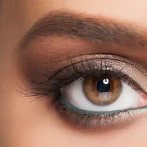 Close-up shot of woman's eye with long natural lashes and green eyeliner