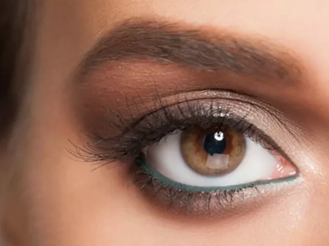 Close-up shot of woman's eye with long natural lashes and green eyeliner