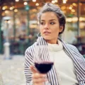 Woman sitting at chic restaurant outdoors with a glass of red wine