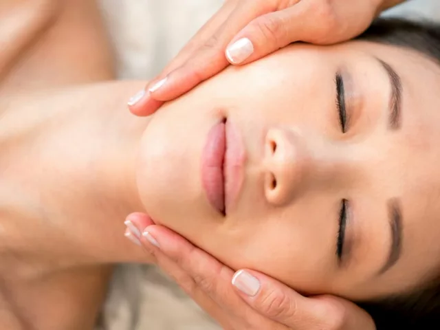 Overhead shot of woman with beautiful skin after microinfusion macial with esthetician holding her face